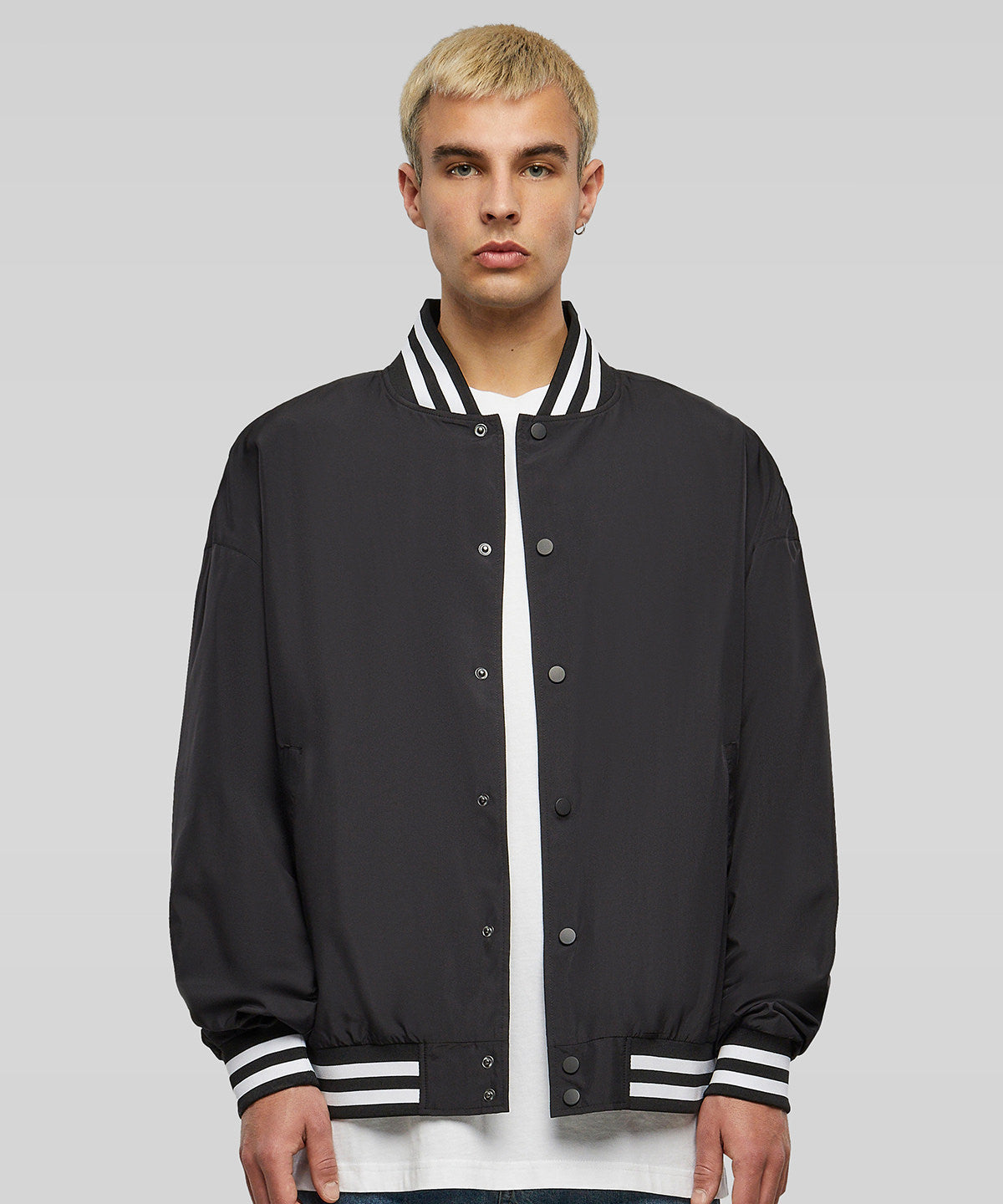 Student wearing black varsity jacket with striped collar and cuffs, ideal for college uniform and campus teamwear.